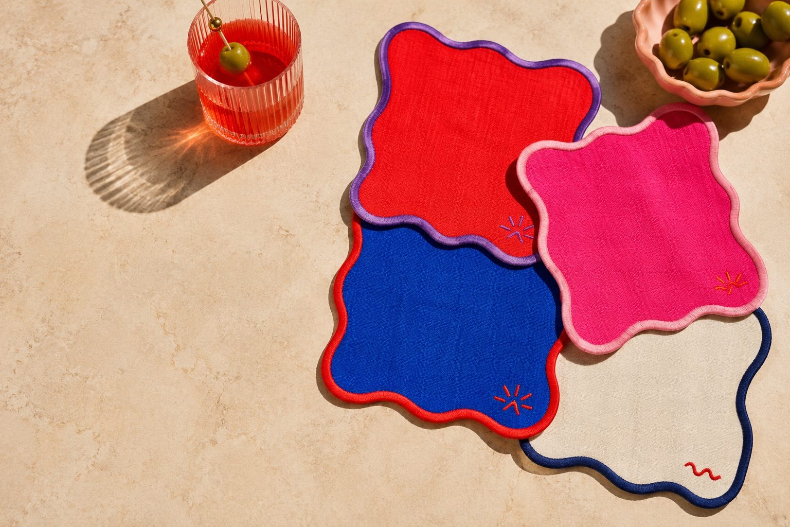 Wavy linen cocktail napkins in red, cobalt and pink on a sunlit table